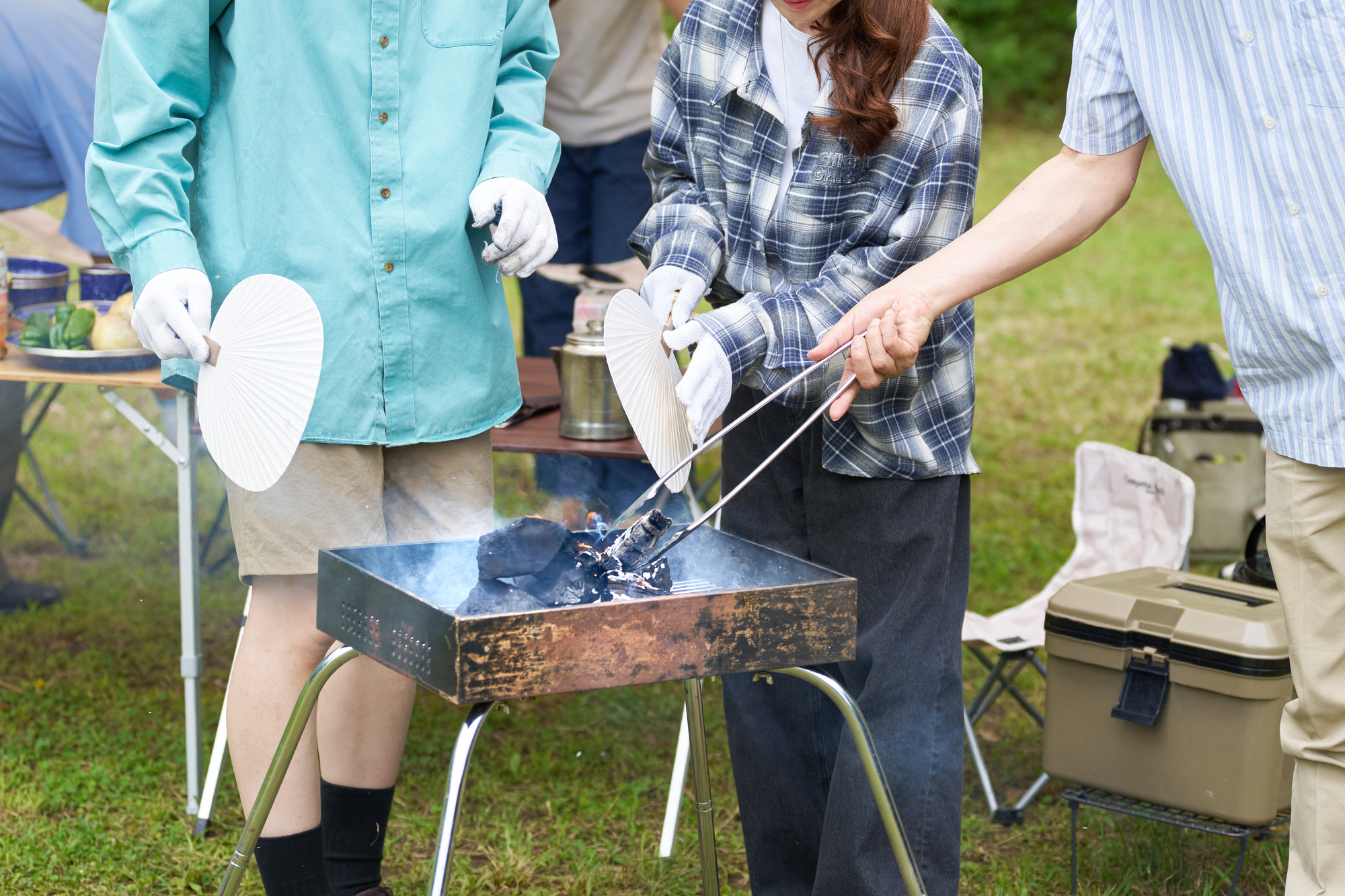 炭火をうちわであおぐ男女の手元